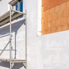 Budowa domu w trakcie, ocieplenie styropianem i cegła klinkierowa. Wiedza, jak obliczyć wylewkę betonową, jest kluczowa.