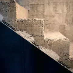Surowe, betonowe schody czekają na wykładzinę. Ich krawędzie są nierówne, a powierzchnia szorstka.