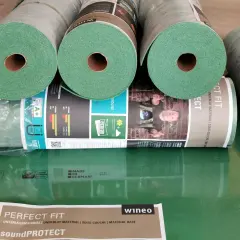 Rolki zielonego podkładu pod panele, idealne do ogrzewania podłogowego. Materiał "Perfect Fit" od wineo zapewnia komfort i izolację.