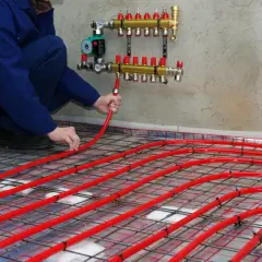 Instalator układa rury podłogówki, dobierając odpowiedni rozdzielacz do ogrzewania 100m2.