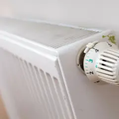 Biały grzejnik z termostatem Honeywell ustawionym na 3. Pokrętło termostatu ma oznaczenia od 1 do 6, z opcją "eco".