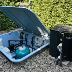 System do podgrzewania wody w basenie: pompa ciepła obok niebieskiej skrzyni z filtrem i instalacją hydrauliczną.
