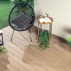Nowoczesne deski kompozytowe to świetne rozwiązanie, co na balkon zamiast płytek. Wygodny fotel, stolik i latarenki tworzą przytulną atmosferę.