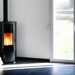 Nowoczesny piec na pellet z płonącym ogniem. Czy piec na pellet można wyłączać na noc? Obok worek z pelletem.