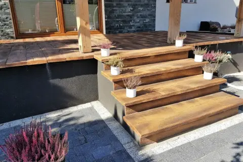 Drewniane schody i taras z kostki brukowej. Idealne rozwiązanie, czym wyłożyć taras, by wyglądał naturalnie i stylowo.