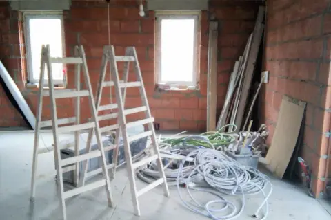 Dwa drewniane rusztowania i plątanina kabli czekają na montaż instalacji w domu.