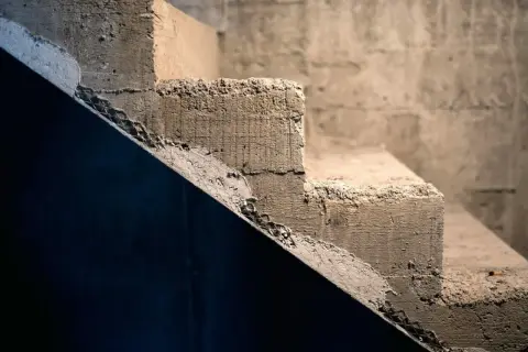 Surowe, betonowe schody czekają na wykładzinę. Ich krawędzie są nierówne, a powierzchnia szorstka.
