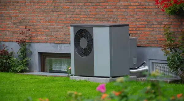 Solidny fundament pod pompę ciepła zapewnia stabilność urządzenia przy ceglanym murze domu.