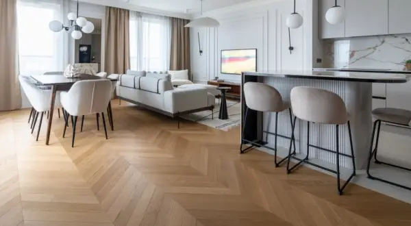 Elegancka jodełka z paneli winylowych, której grubość podkreśla jakość. Salon z sofą, jadalnia i barek kuchenny.