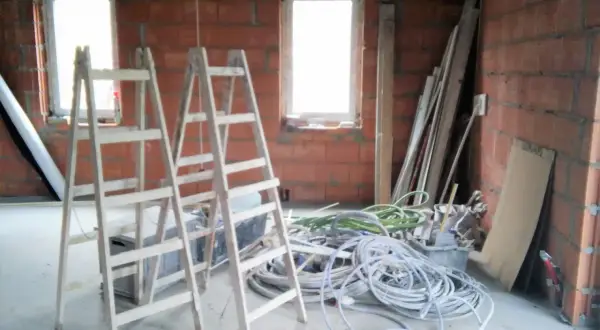 Dwa drewniane rusztowania i plątanina kabli czekają na montaż instalacji w domu.