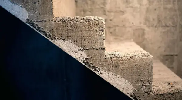 Surowe, betonowe schody czekają na wykładzinę. Ich krawędzie są nierówne, a powierzchnia szorstka.