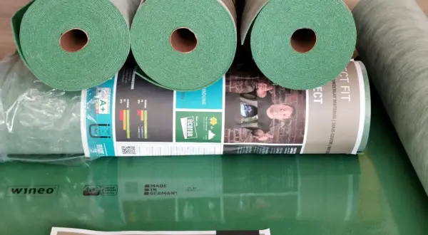 Rolki zielonego podkładu pod panele, idealne do ogrzewania podłogowego. Materiał "Perfect Fit" od wineo zapewnia komfort i izolację.
