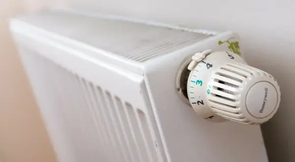 Biały grzejnik z termostatem Honeywell ustawionym na 3. Pokrętło termostatu ma oznaczenia od 1 do 6, z opcją "eco".