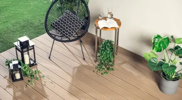 Nowoczesne deski kompozytowe to świetne rozwiązanie, co na balkon zamiast płytek. Wygodny fotel, stolik i latarenki tworzą przytulną atmosferę.