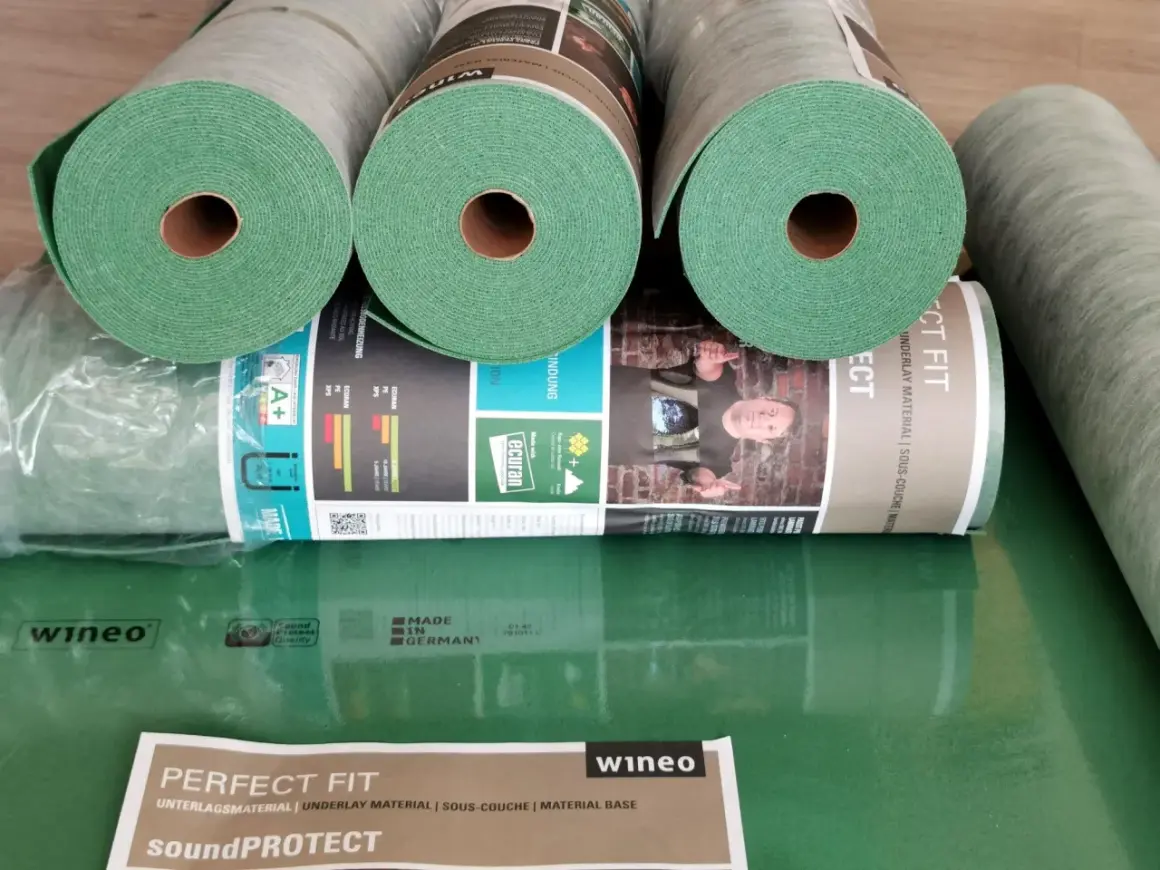 Rolki zielonego podkładu pod panele, idealne do ogrzewania podłogowego. Materiał "Perfect Fit" od wineo zapewnia komfort i izolację.
