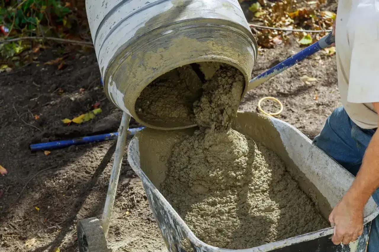 Mieszanka cementowa wylewana z betoniarki do taczki. Idealny materiał, jeśli zastanawiasz się, jaki cement na wylewki będzie najlepszy.