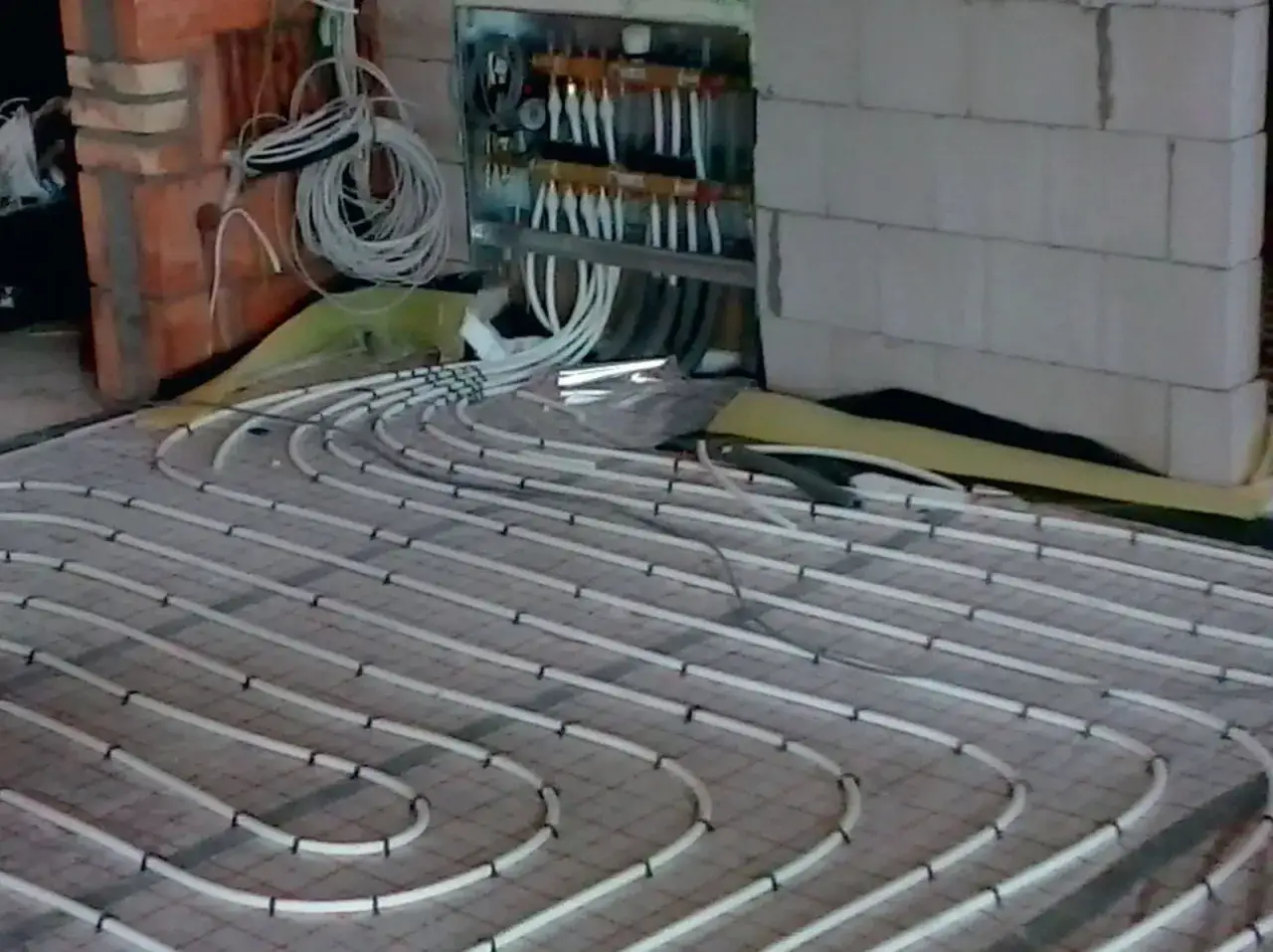 Instalacja ogrzewania podłogowego elektrycznego. Widać rurki ułożone na siatce, przygotowane do zalania. Zastanawiasz się nad ogrzewanie podłogowe elektryczne koszty miesięczne?