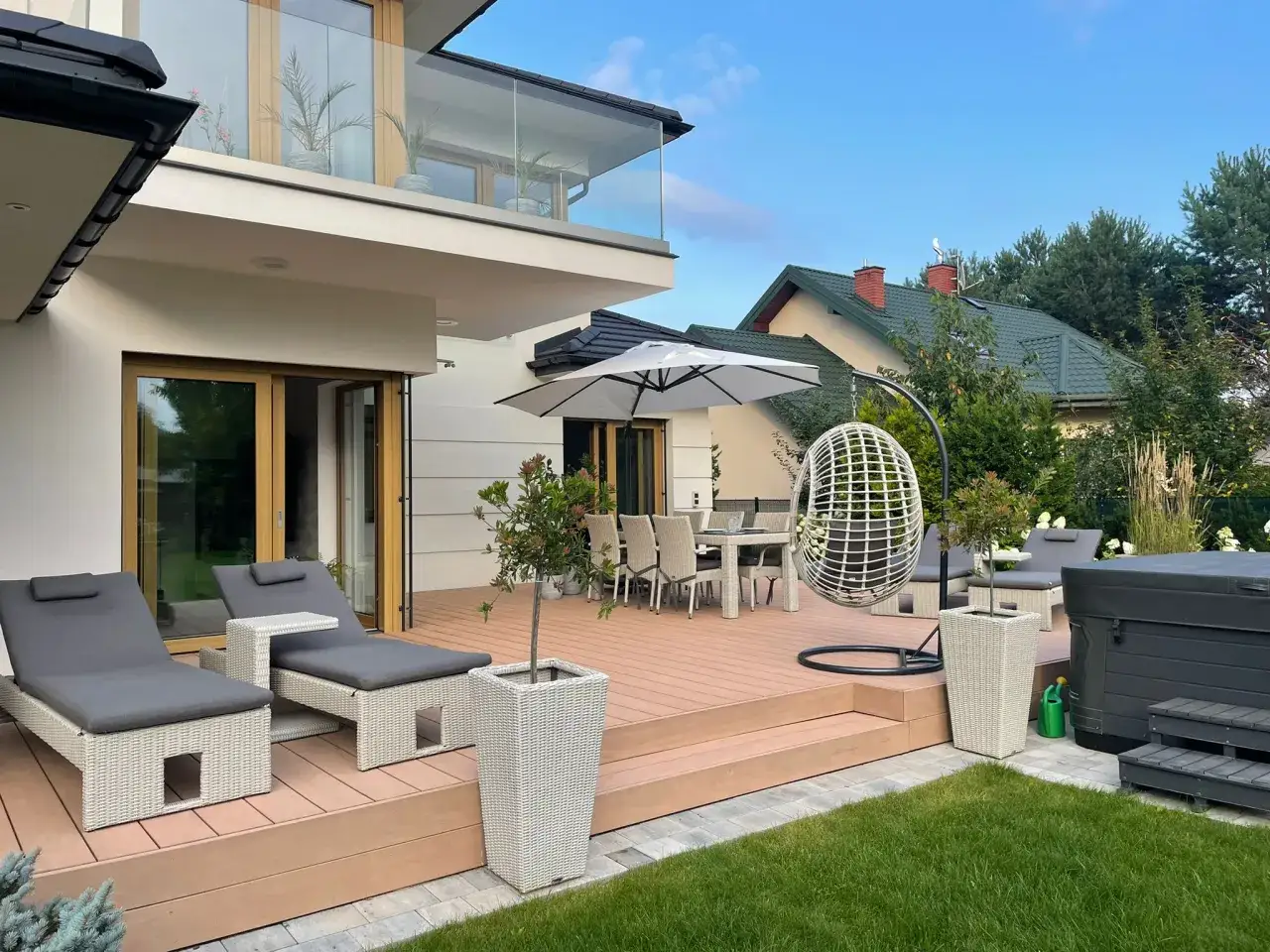 Nowe taras inspiracje: leżaki, stół z krzesłami, huśtawka i jacuzzi tworzą idealne miejsce do relaksu.