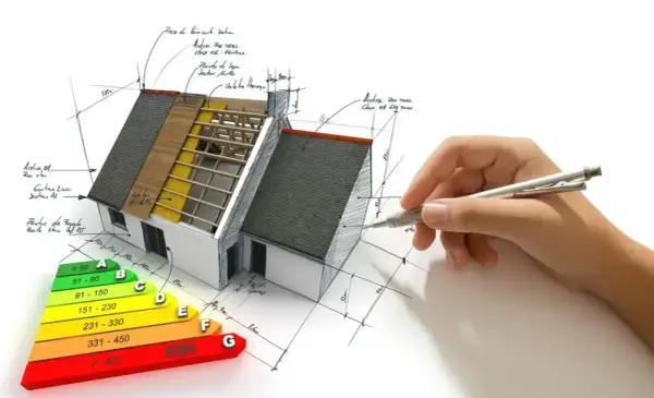 Projektowanie domów energooszczędnych: model domu z widocznym ociepleniem, schematem klasyfikacji energetycznej i ręką rysującą plany.