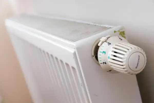 Biały grzejnik z termostatem Honeywell ustawionym na 3. Pokrętło termostatu ma oznaczenia od 1 do 6, z opcją "eco".